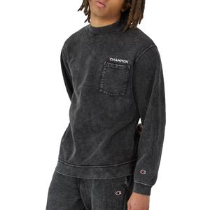 A black, washed sweatshirt from Champion featuring a chest pocket with the brand's logo, crew neck, and long sleeves. The Champion emblem also appears on the sleeve.