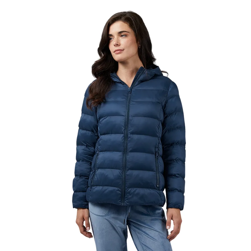 A woman wears a navy blue puffer jacket with a zip front and two side pockets, paired with light blue pants.