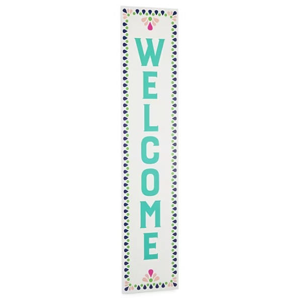 A vertical \“WELCOME\“ sign with teal letters, bordered by a pattern of blue and green shapes, and small floral accents at the top and bottom.