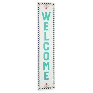 A vertical \“WELCOME\“ sign with teal letters, bordered by a pattern of blue and green shapes, and small floral accents at the top and bottom.