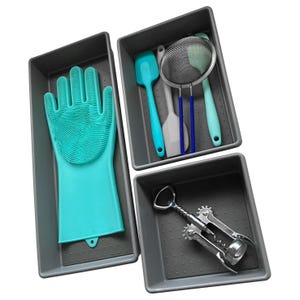 Three gray drawer organizers contain a silicone cleaning glove, spatulas, a mesh strainer, and a corkscrew.