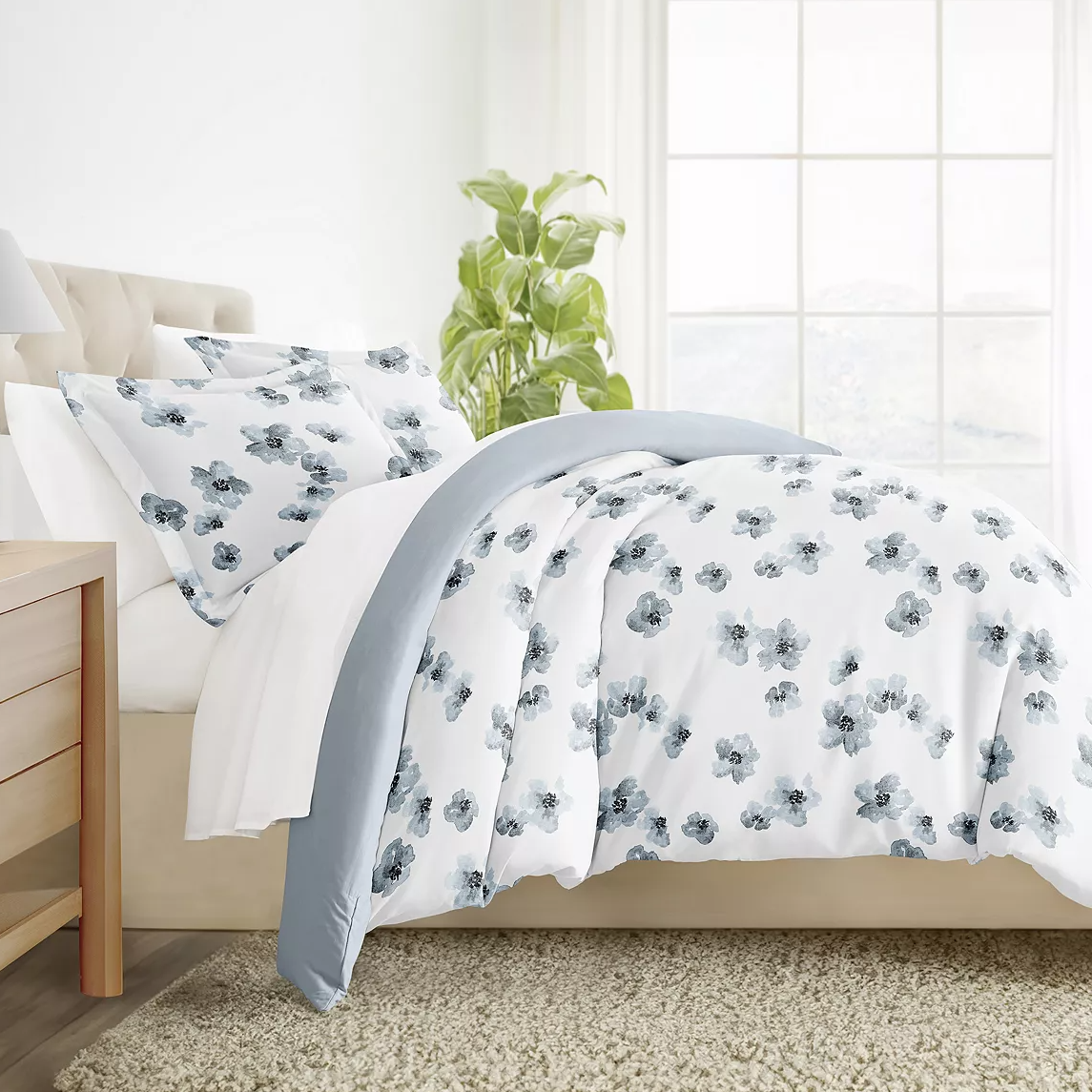 A floral patterned bedding set with pillows and a duvet cover in a white and blue color scheme.