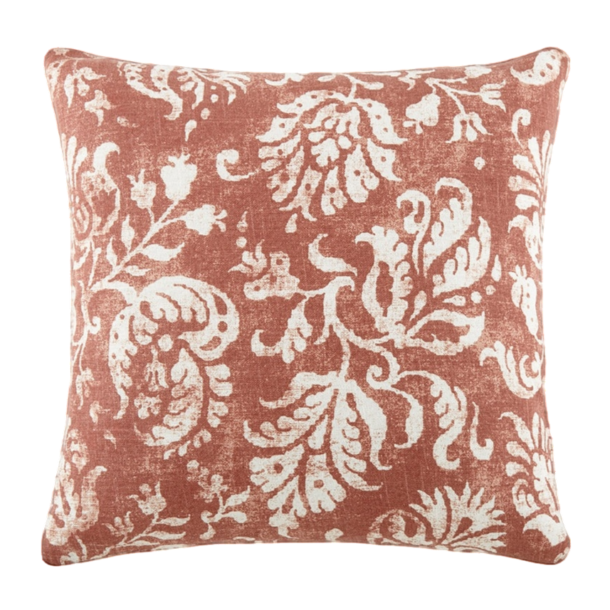 A square decorative pillow with a rust-colored background and white floral pattern.