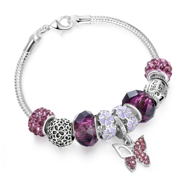 A silver bracelet with a variety of purple and silver charms, including a crystal butterfly pendant, floral designs, and bead accents.