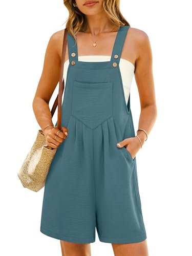 A woman is wearing teal short overalls with front buttons and pockets, paired with a white tube top. She carries a woven straw bag and wears a necklace.