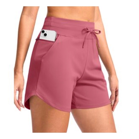Woman wearing pink athletic shorts with a drawstring waistband and a side pocket holding a smartphone.