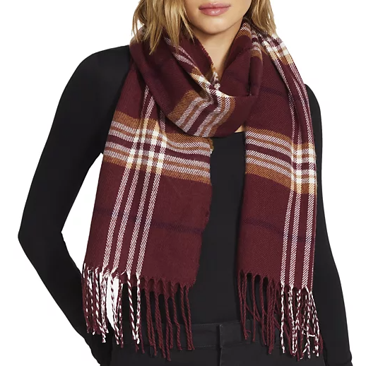 A woman wearing a burgundy plaid scarf with fringe over a black top.