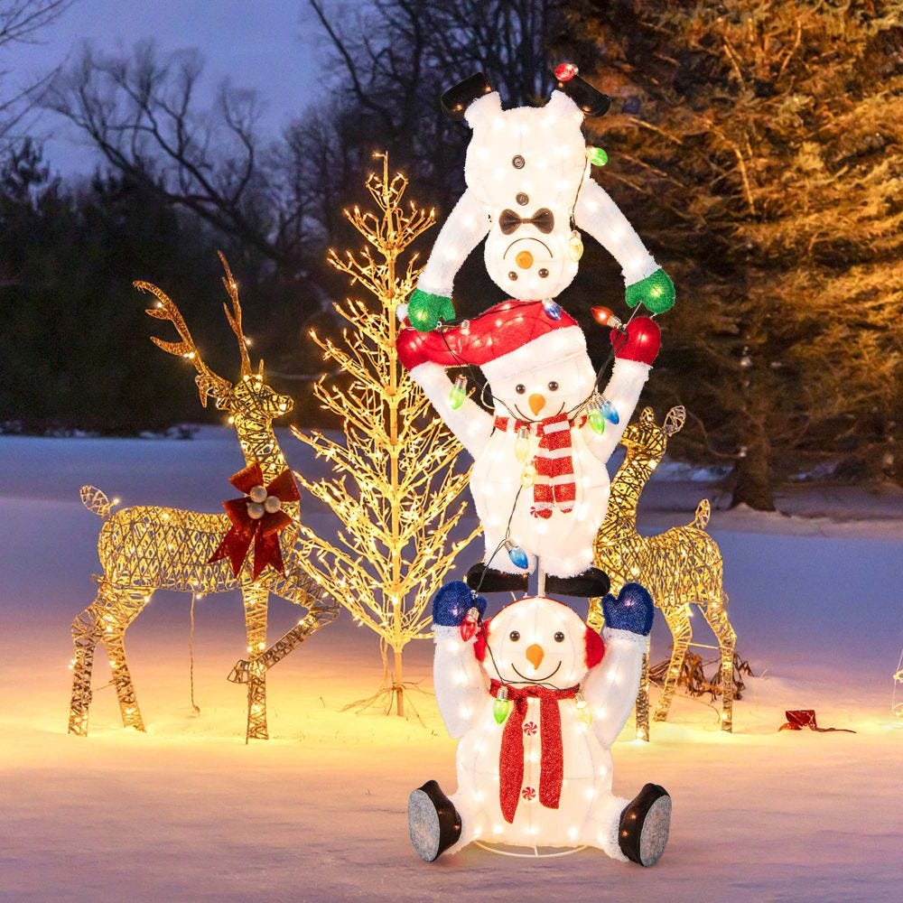 Illuminated snowmen stack with colorful lights and two wireframe reindeer adorned with Christmas accents, set outdoors with a glowing tree in the background.