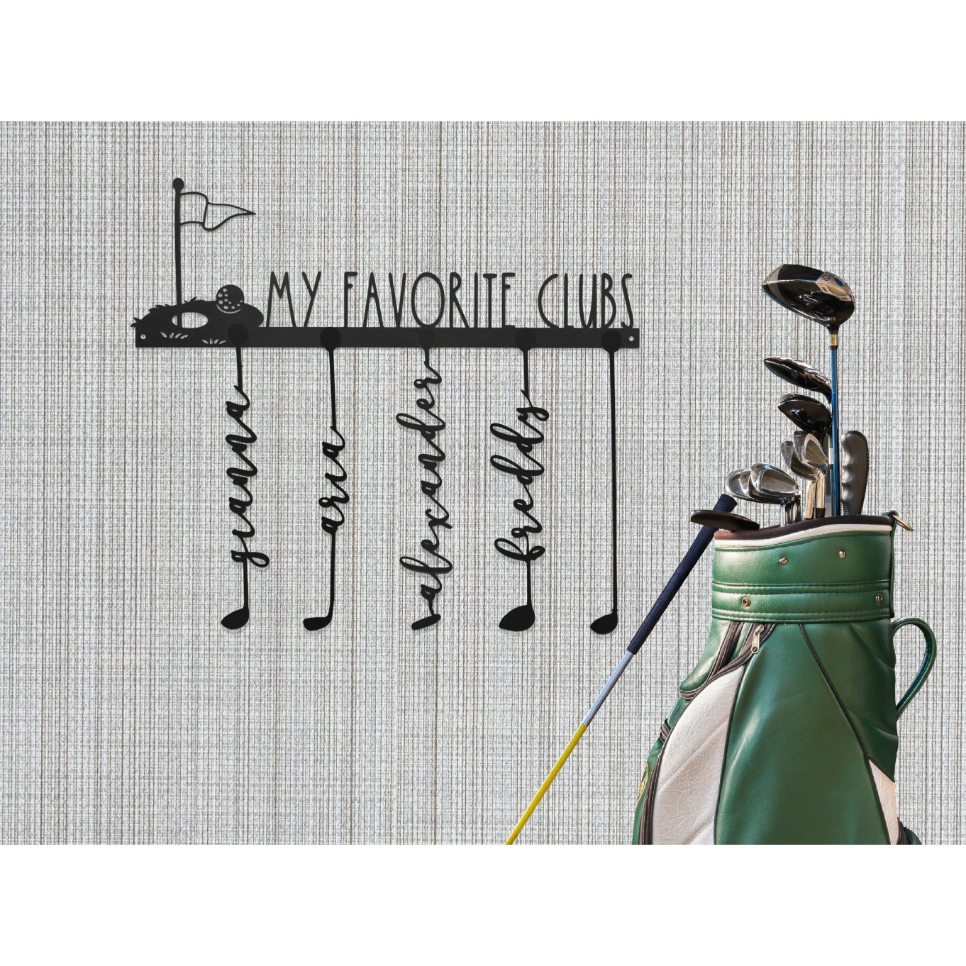 A metal wall sign features the text \“My Favorite Clubs\“ with a golf cart and flag design. Below are hooks shaped like golf clubs with names: guama, rose, alexander, and freddy. A green golf bag with various clubs stands beside the sign.