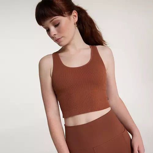 A woman wearing a brown cropped tank top with matching high-waisted leggings.