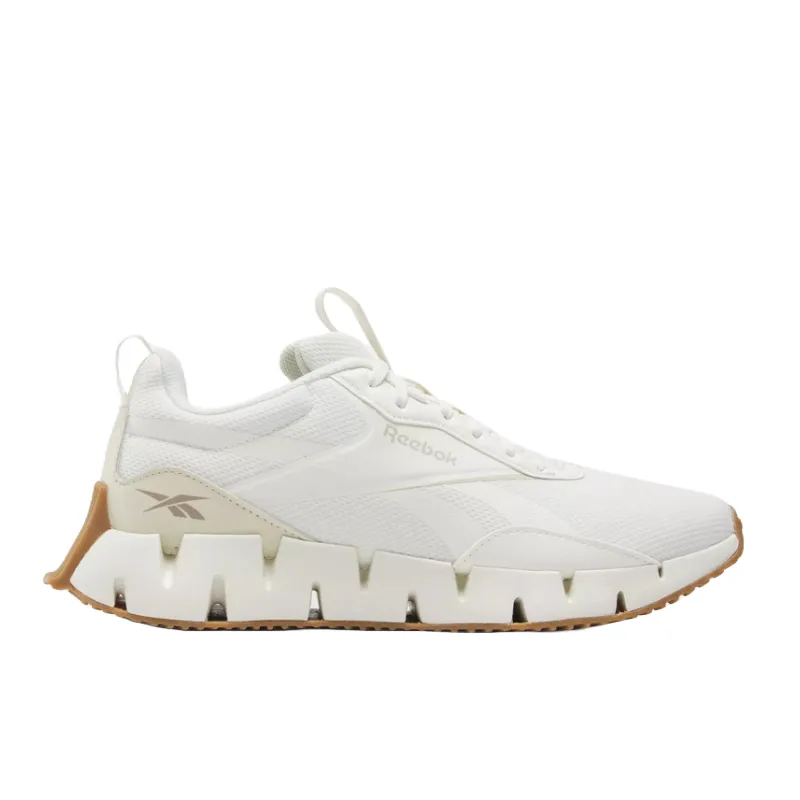 White Reebok Zig Dynamica STR shoes feature a low-cut, breathable mesh upper with subtle branding, a distinctive zigzag midsole for cushioning, and a gum outsole for traction.