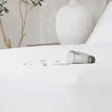 A waterproof mattress protector with a spilled glass of water on it, demonstrating its liquid-resistant feature.