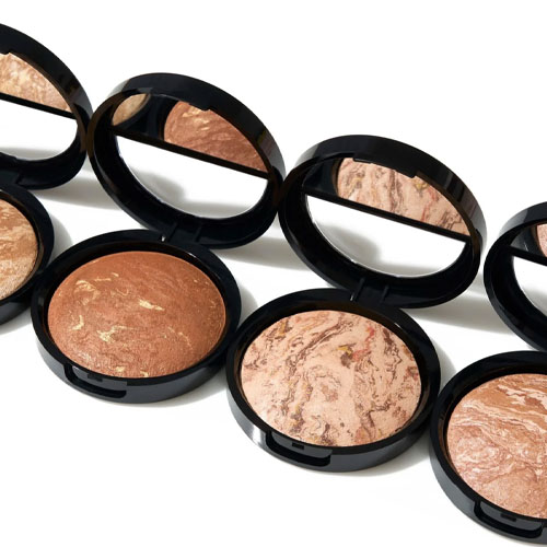 Open compacts of marbleized powder makeup with mirrors in the lids, displaying various shades from light to dark.