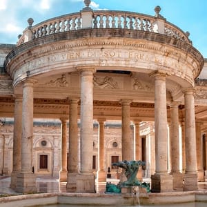Classical circular pavilion with Corinthian columns and a central sculpture, located within a larger architectural complex.