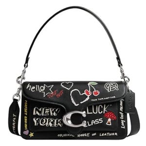 Black shoulder bag with various embroidered designs, including words like \“New York,\“ a cherry, a heart, and a mushroom. Features a prominent silver \“C\“ clasp and a detachable strap with chain details.
