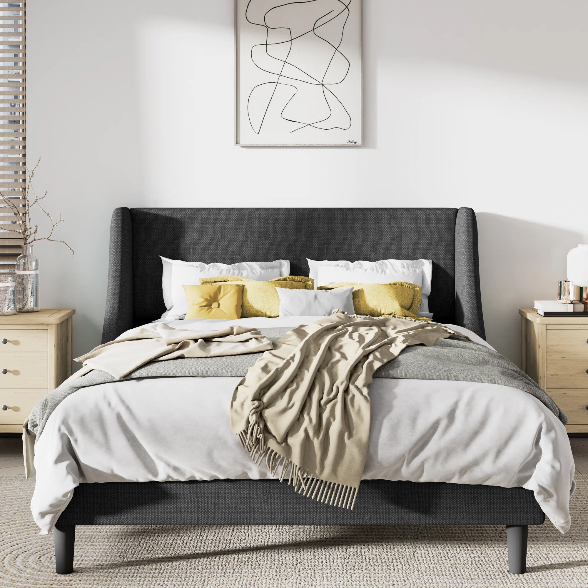 A modern bedroom setup with a dark upholstered bed, white and yellow bedding, a pair of wooden nightstands, and a wall art piece above the bed.