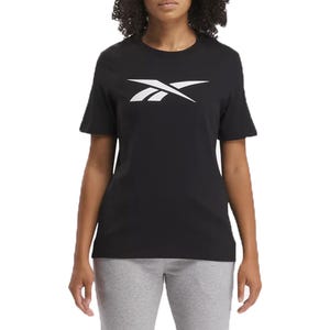 A woman is wearing a black Reebok t-shirt with a large white logo on the front, paired with gray pants.