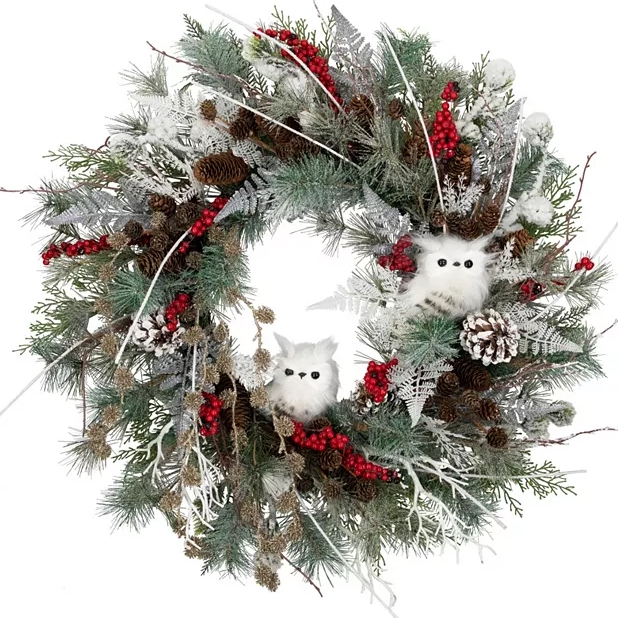 A festive wreath with artificial greenery, pinecones, red berries, and two white owl decorations.