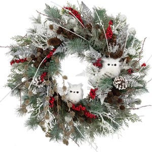 A festive wreath with artificial greenery, pinecones, red berries, and two white owl decorations.