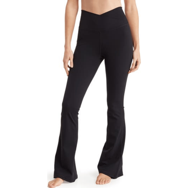Black crossover flared leggings with a high-waisted design featuring a V-shaped waistband. The pants have a snug fit through the thighs and flare out towards the ankles.