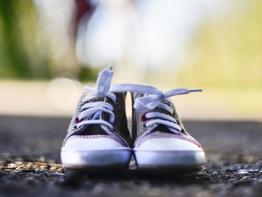 A pair of gray canvas sneakers with white laces and white rubber soles.
