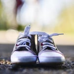 A pair of gray canvas sneakers with white laces and white rubber soles.