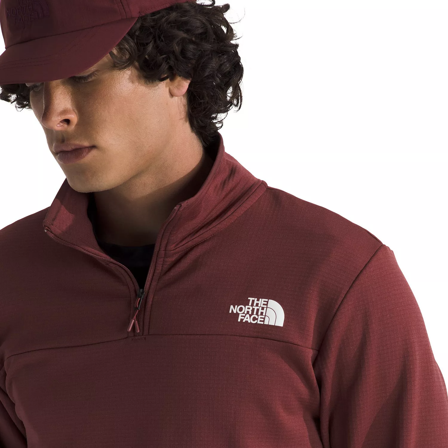 A person wearing a maroon North Face pullover with a quarter-zip and a matching cap.