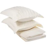 A stack of cream-colored, quilted bedding items including two pillows and a folded blanket.