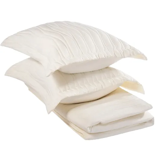 A stack of cream-colored, quilted bedding items including two pillows and a folded blanket.