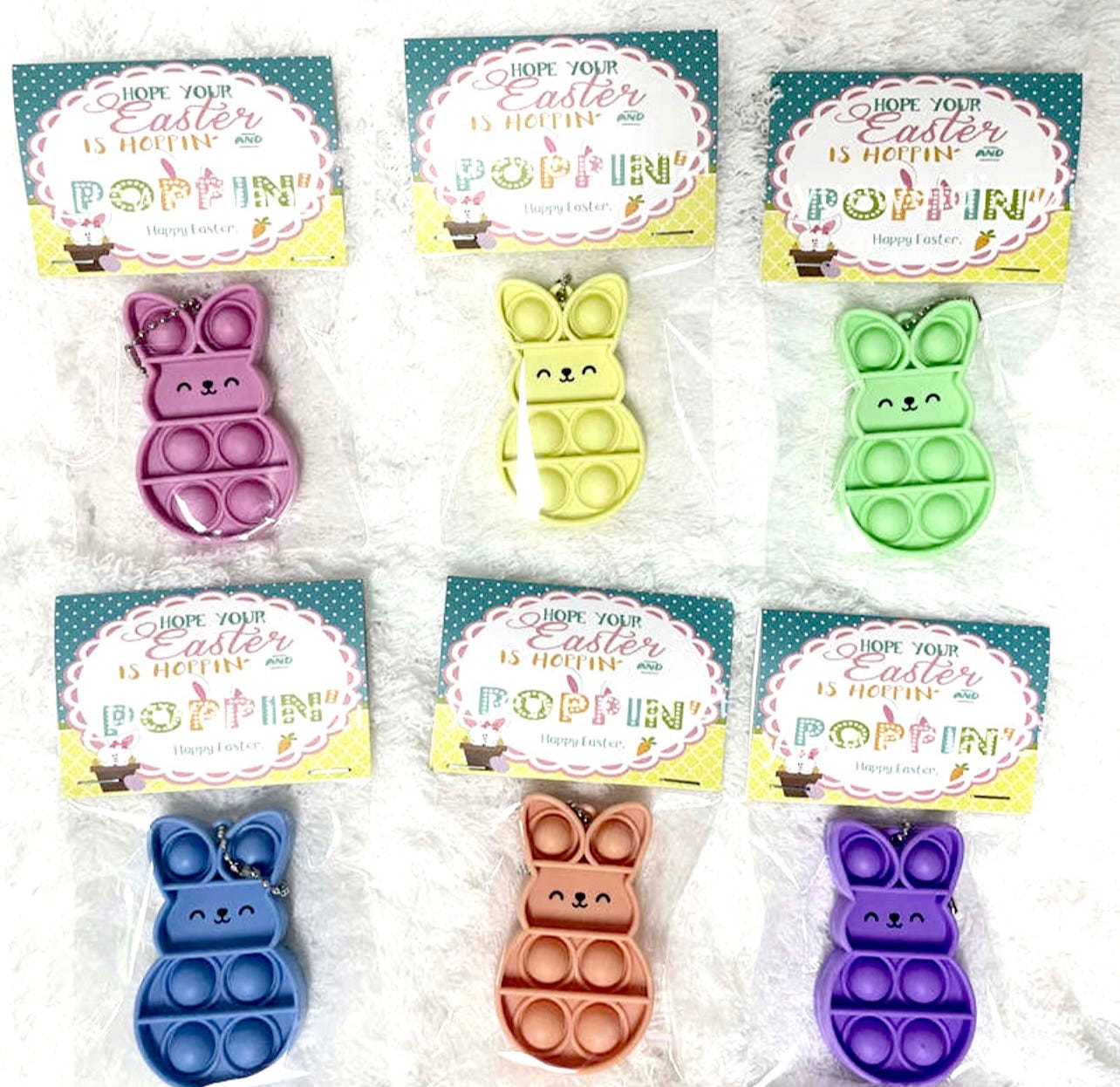 Easter-themed bubble pop fidget toys shaped like bunnies in various colors, attached to cards with festive greetings.