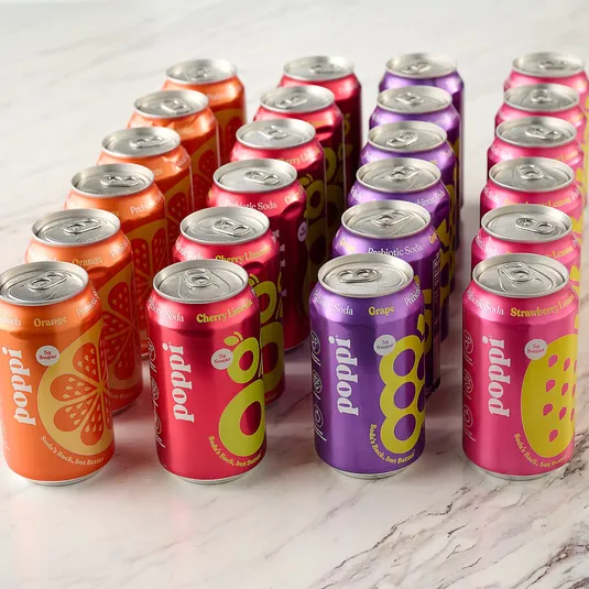 Cans of \“poppi\“ prebiotic soda with flavors: Orange, Cherry Limeade, Grape, and Strawberry Lemonade, each containing 5g of sugar.