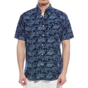 A short-sleeve button-up shirt with a navy blue background and light blue floral pattern, worn by a person with white pants.