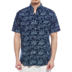 A short-sleeve button-up shirt with a navy blue background and light blue floral pattern, worn by a person with white pants.