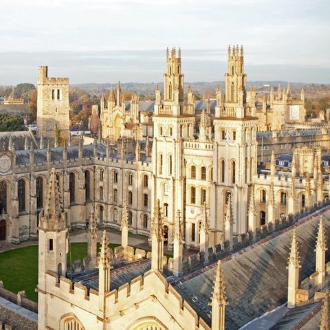 The image shows the beautiful architecture of a historic university building with tall towers and intricate stonework.