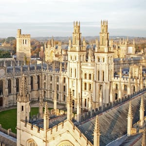 The image shows the beautiful architecture of a historic university building with tall towers and intricate stonework.