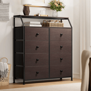 A dark brown dresser with eight drawers featuring black knobs stands on a wooden floor. It has a metal frame, and is topped with a shelf displaying a lamp, books, a basket, and flowers in a vase.
