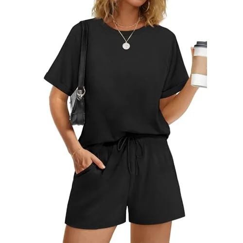 A person is wearing a black short-sleeve top and matching shorts with a drawstring waist, holding a cup and a black shoulder bag.