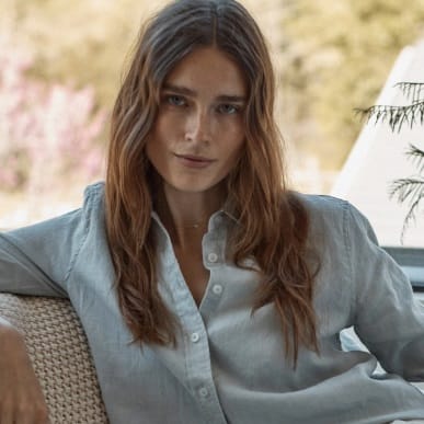 A woman is wearing a casual light gray button-down shirt.