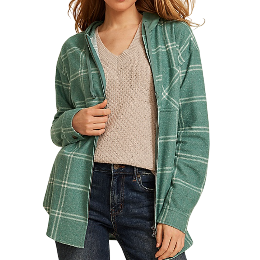 A woman wearing a green plaid hooded jacket over a textured beige V-neck sweater, paired with blue jeans.