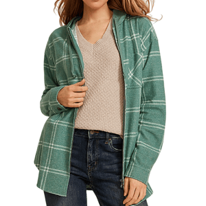 A woman wearing a green plaid hooded jacket over a textured beige V-neck sweater, paired with blue jeans.