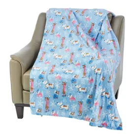 A light blue fleece blanket with a pattern of cartoon dogs and snowflakes is draped over a beige armchair.