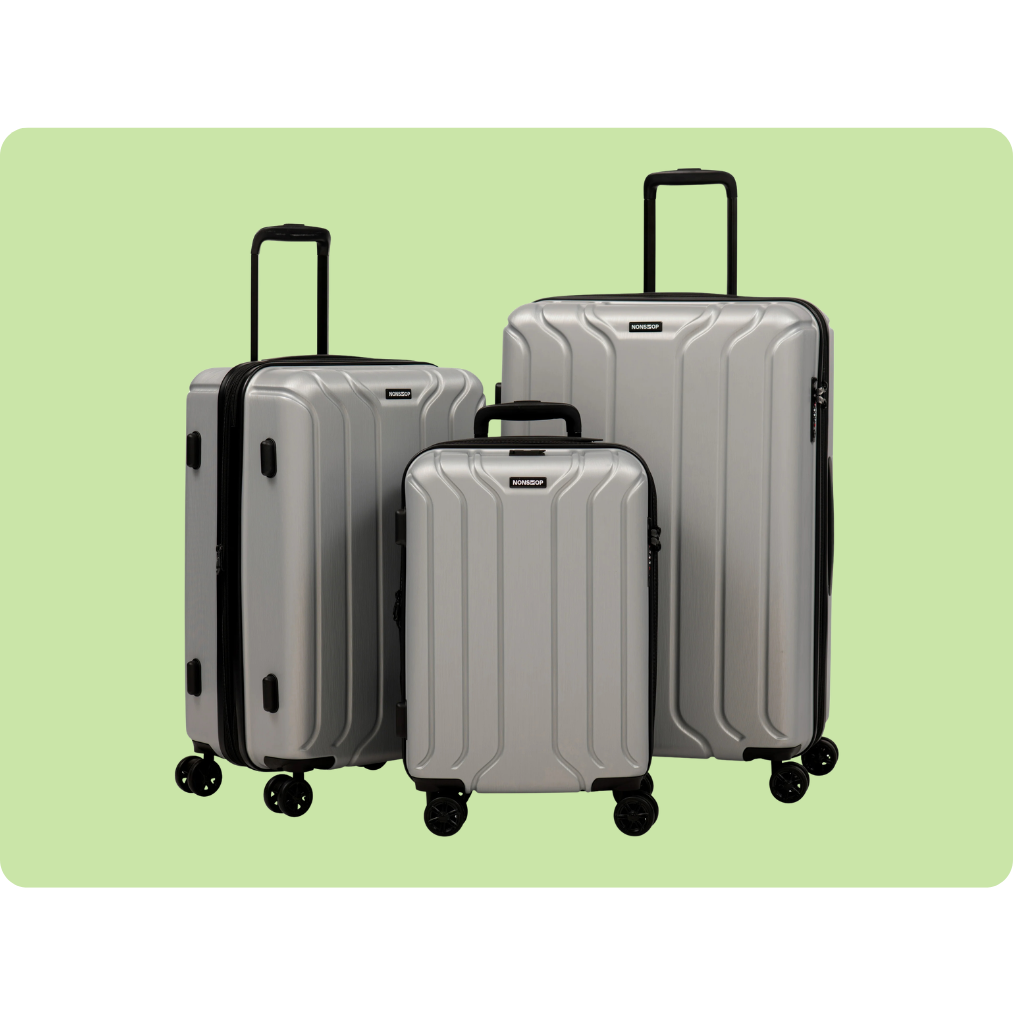 A set of three silver hard-shell suitcases with black handles and wheels, displayed against a light green background.