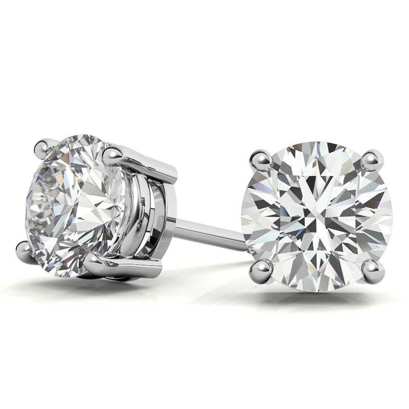 A pair of round-cut diamond stud earrings set in a four-prong white metal setting, showcasing clear and reflective gemstones.