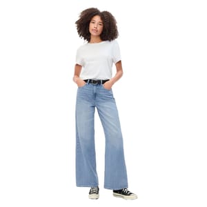 A person is wearing a white T-shirt, light blue wide-leg jeans, a black belt, and black low-top sneakers.