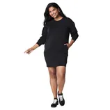 A woman is wearing a black long-sleeve sweatshirt dress with pockets, paired with black sneakers featuring white laces.
