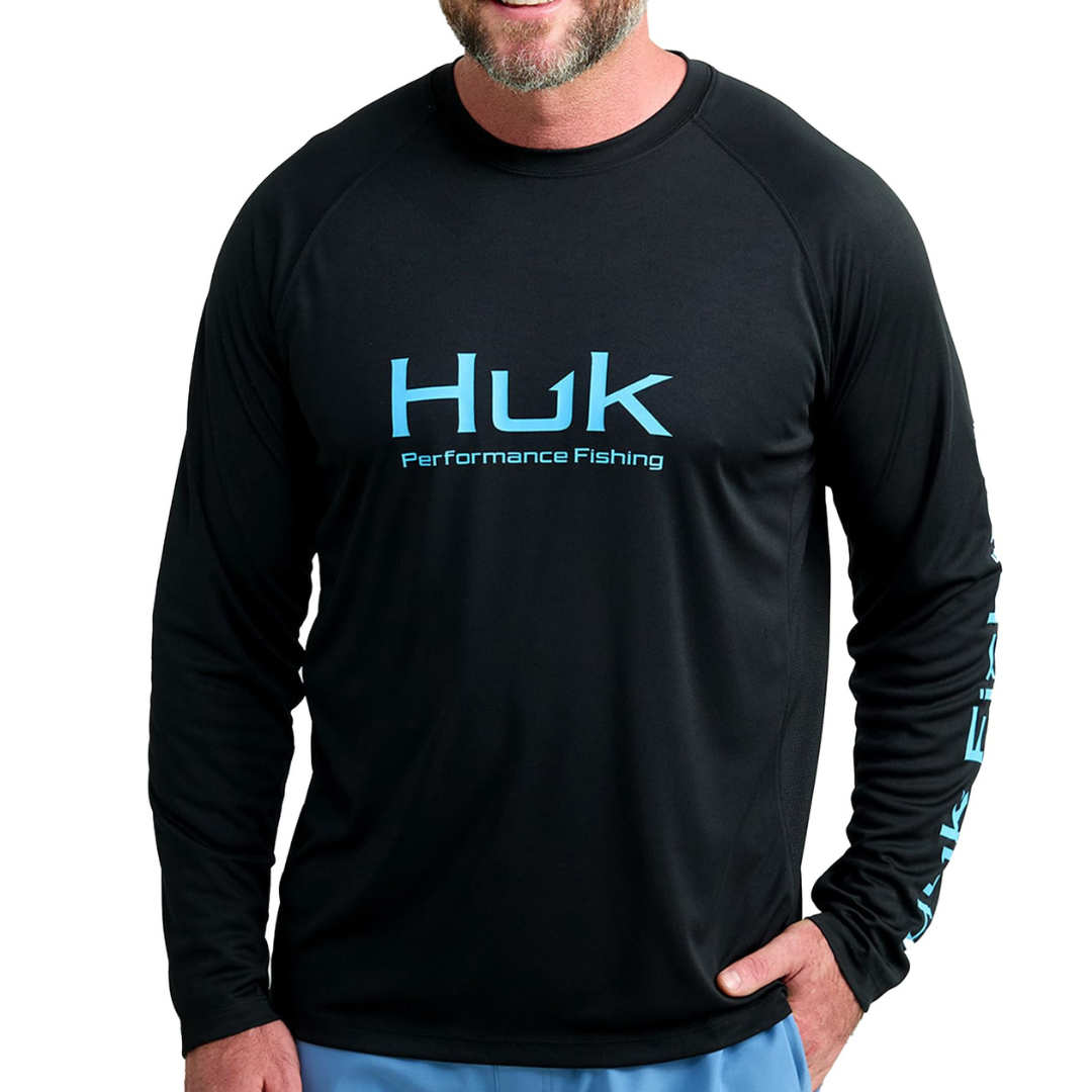 Black long-sleeve shirt with \“Huk Performance Fishing\“ in blue text on the front and sleeve, paired with light blue pants.