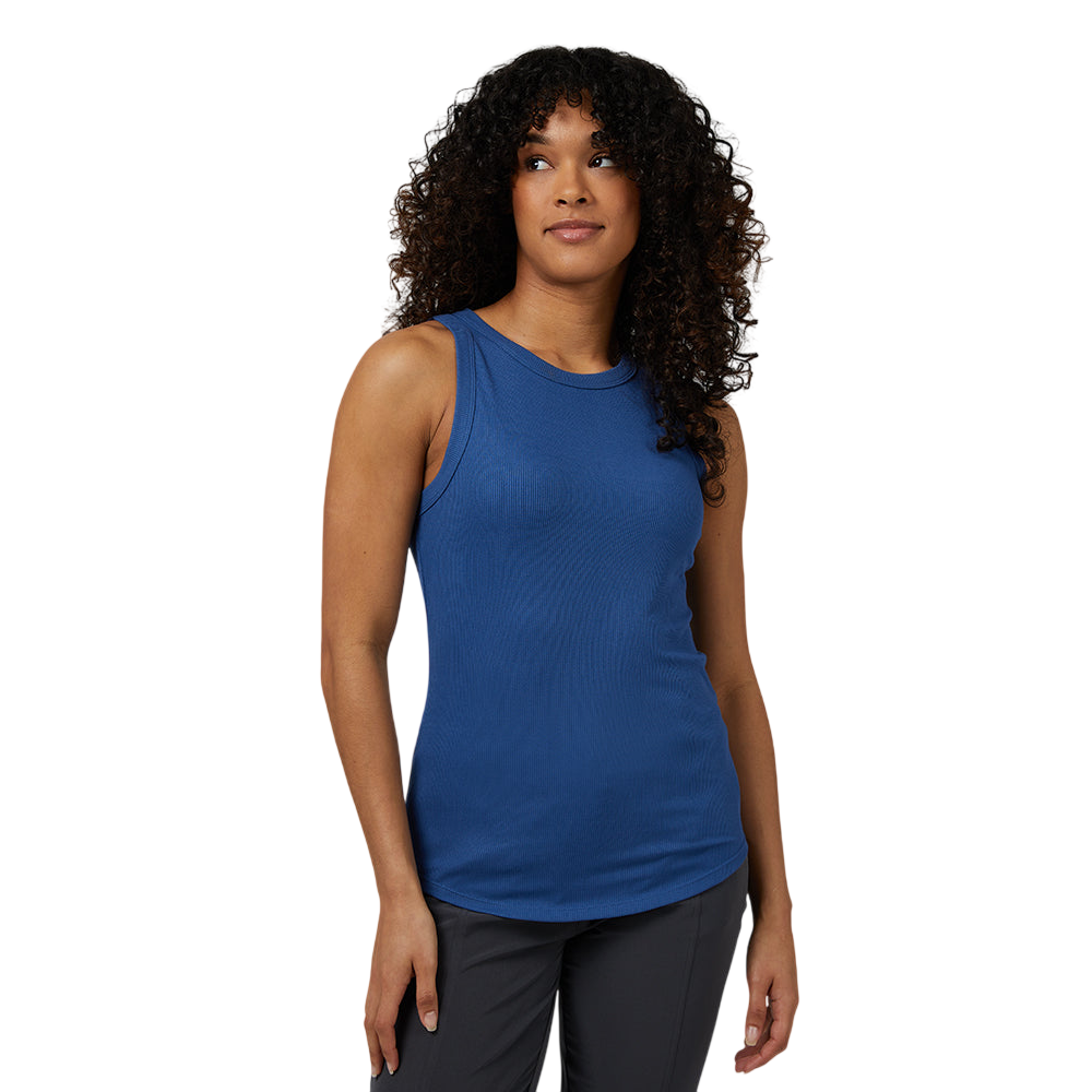 A person is wearing a sleeveless, blue tank top paired with dark pants. The background is a solid gray.