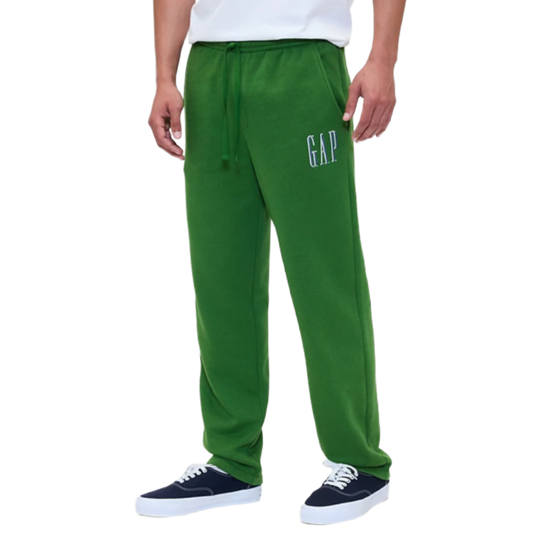 Green sweatpants with \“GAP\“ logo on the left thigh, featuring a drawstring waist. Styled with blue and white sneakers and a white shirt.