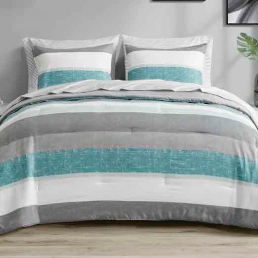 A bed is adorned with striped bedding in shades of gray, white, and teal. Matching pillows complement the comforter with similar patterns.