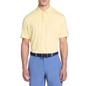 A man wears a light yellow polo shirt and blue pants, accessorized with a dark blue textured belt.
